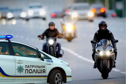 Патрульний автомобіль поліції та мотоциклісти на вечірній міській дорозі