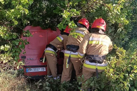 Рятувальники біля червоного пікапа, що заїхав у кущі біля дороги