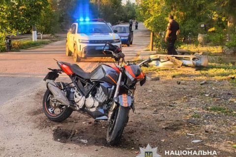 Червоно-чорний мотоцикл на дорозі біля поліцейської машини