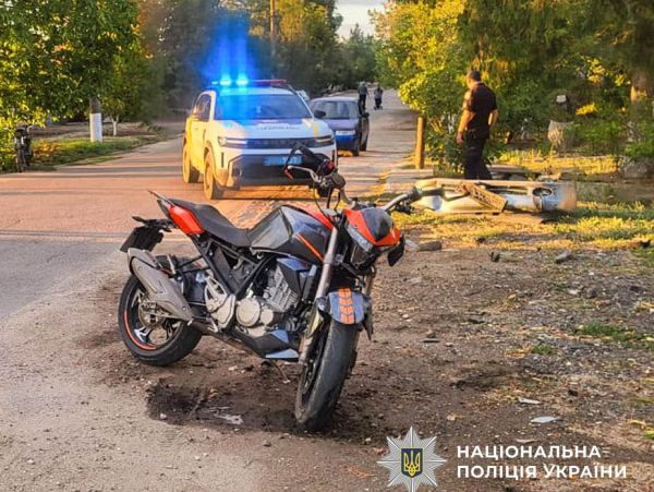 Червоно-чорний мотоцикл на дорозі біля поліцейської машини