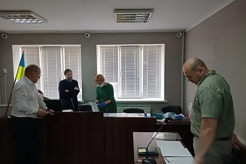 Засідання в залі суду з прапором України, столами, документами та мікрофонами