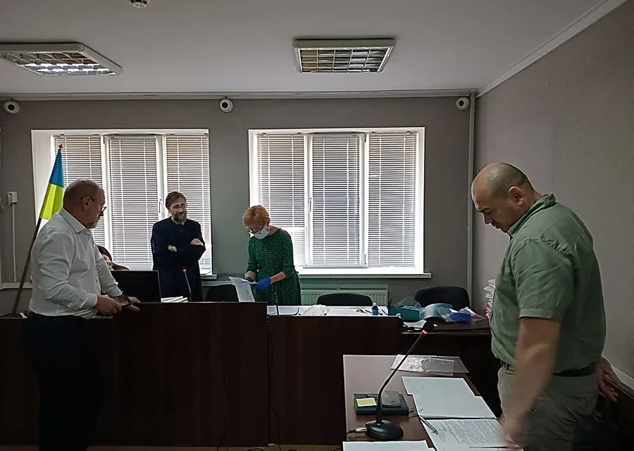 Засідання в залі суду з прапором України, столами, документами та мікрофонами