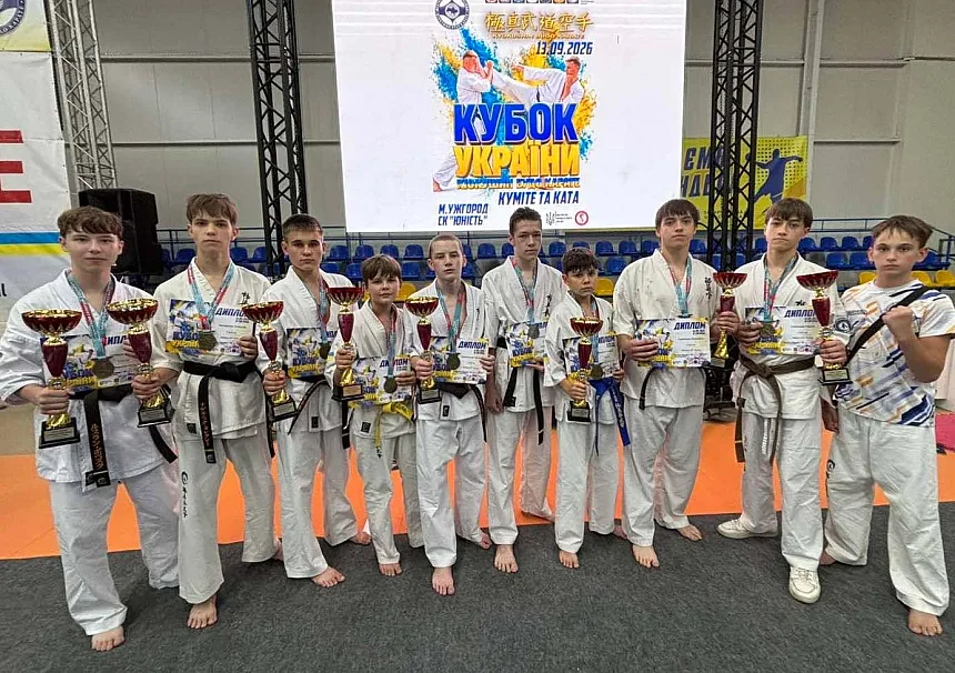 Юні каратисти з кубками та дипломами на тлі банера Кубка України в Ужгороді